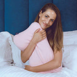 Glückliche Frau im Bett mit einem smart® Recovery Pillow in passgenauem Wechselbezug smart® Recovery Pillow Case in der Farbe Rose